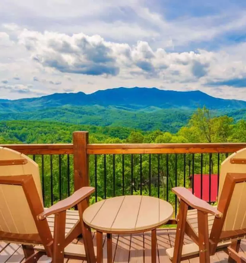 two chairs facing mountain views on the porch of a cabin