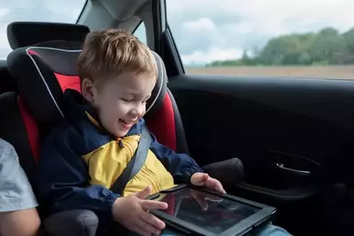 little boy playing in car with tablet