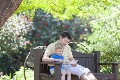 Father and son reading a map on a bench.