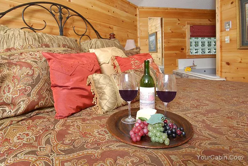 wine and grapes on a bed in the Honeymoon Hideaway cabin