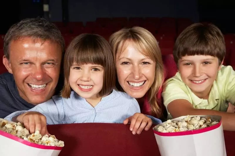 Family eating popcorn in a movie theater