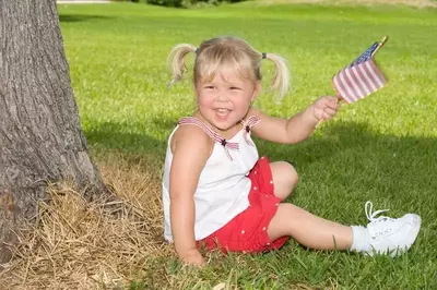 Cute little girl waving the American flag in a park