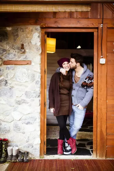 Couple standing in doorway of cabin with man kissing girl