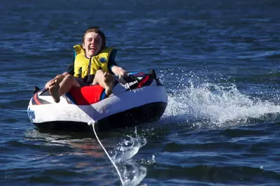 Boy Enjoying Skiing on Inflatable Behind Speed Boat
