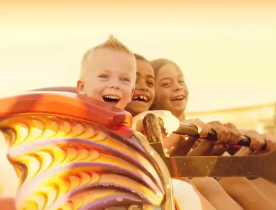 Kids in a roller coaster in the sunset