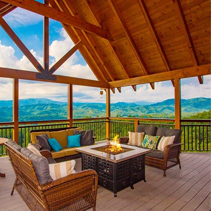 outdoor furniture around fire pit on cabin deck with mountains in background