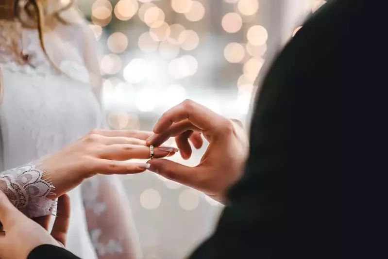 man placing a ring on his bride's hand at a wedding