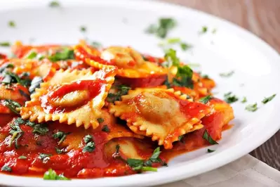 A plate of ravioli with marinara sauce.