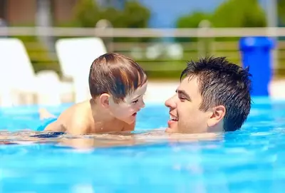 Father and son playing in a pool during the summer
