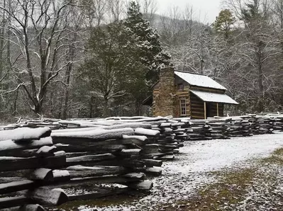 Snow covered cabin and fence in Cades Cove in winter.