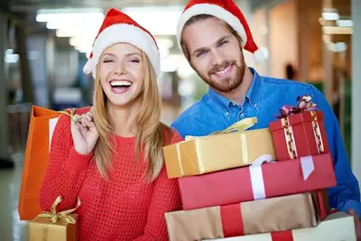 Happy couple in Santa hats with Christmas gifts.