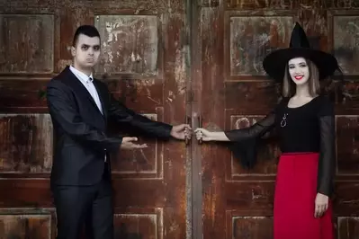Vampire and witch holding the door of a haunted house.
