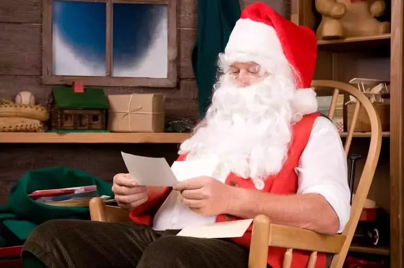 Santa Claus reading a letter in his workshop.