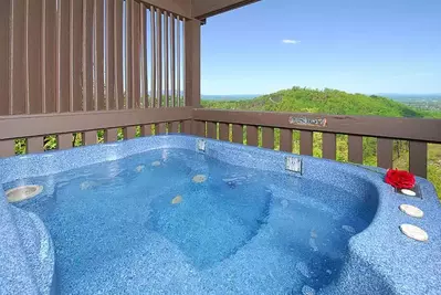 A hot tub on deck of Mountains Majesty, one of our cabins in Gatlinburg with mountain views.