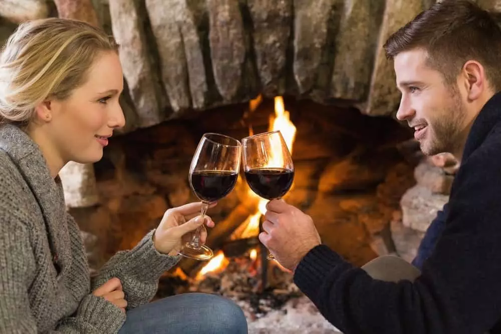 Couple drinking wine by the fireplace in their honeymoon cabin in Gatlinburg