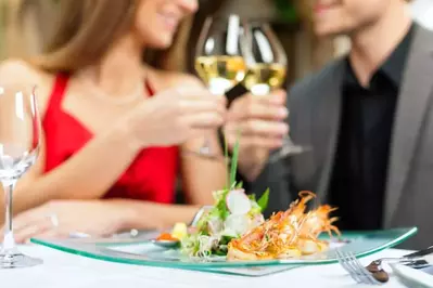 Couple enjoying a romantic dinner for 2 with glasses of white wine in a Pigeon Forge cabin