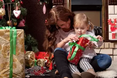 Little girl getting Christmas gift with mother