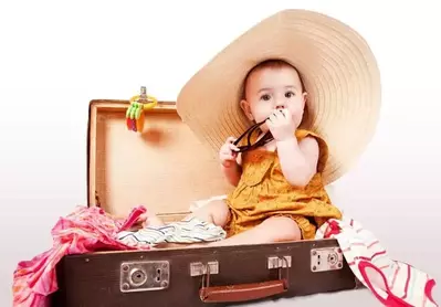 baby with sun hat in suitcase