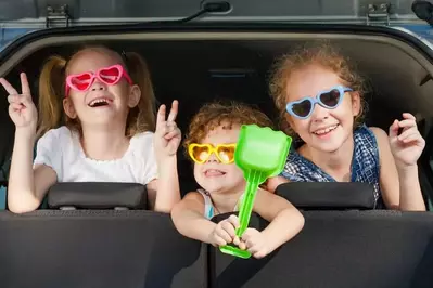 two little girls and boy sitting in the car