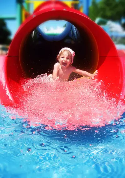 Baby girl going down red water slide