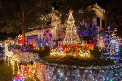 Christmas lights decorating a white house and the yard