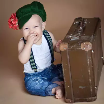 Cute little boy with the flower sitting on an old suitcase.