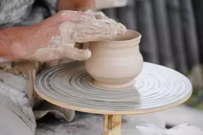 Hands making pottery