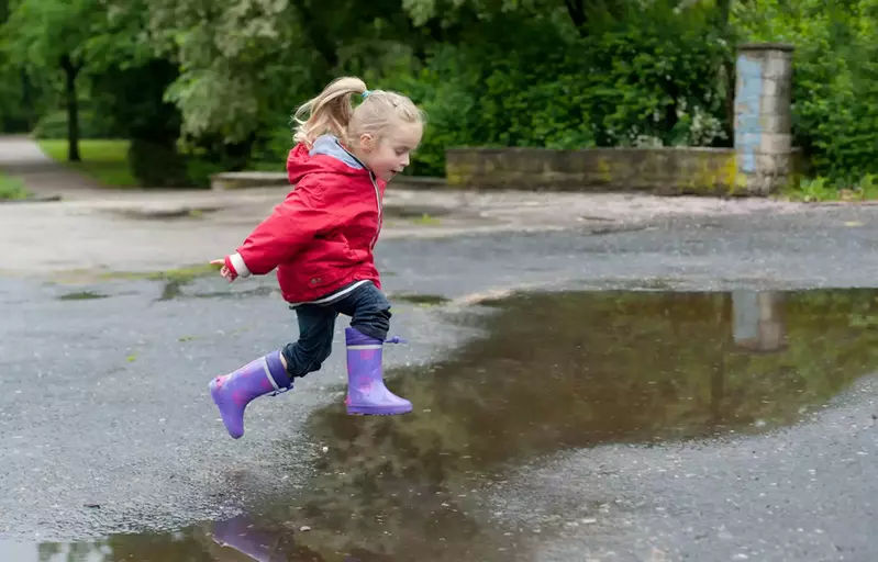 Little girl jumping in a puddle