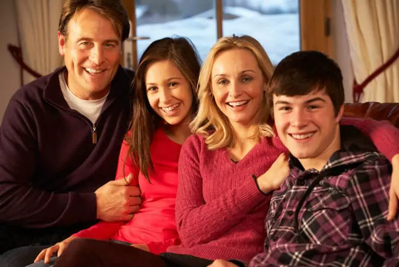 family posing on the sofa in front of a winter backdrop in a Pigeon Forge cabin with internet access