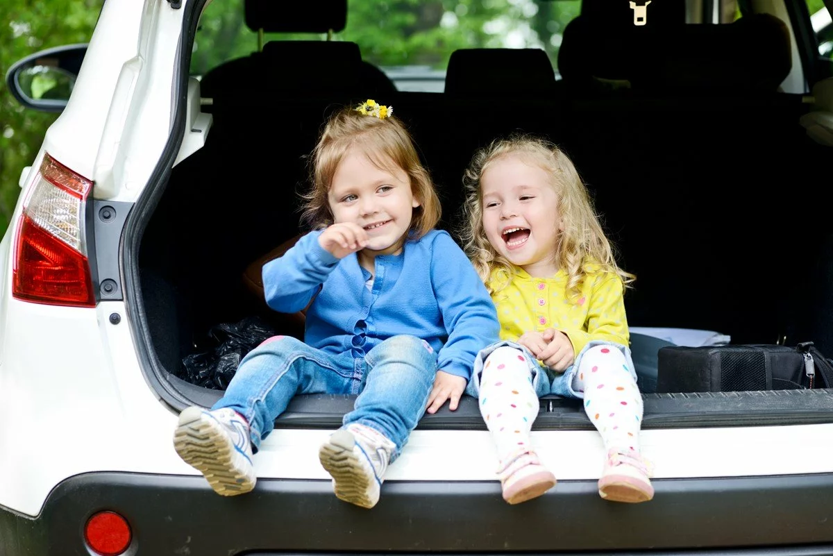 Laughing toddlers in back seat of car