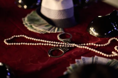 hats, money, necklace and handcuffs on a table